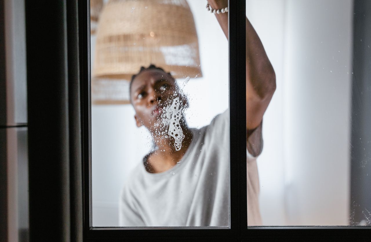services-02 An adult male cleaning a glass window indoors, focusing on household chores and cleanliness.